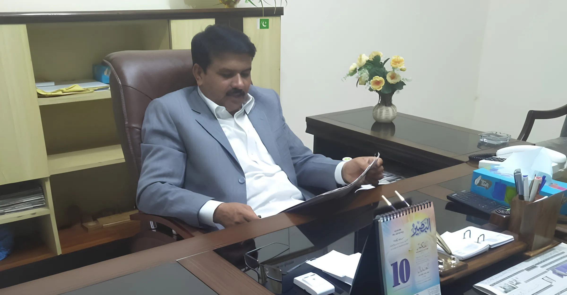 Ch. Shams Ul Haq Shahid reading case papers at his desk in chambers.